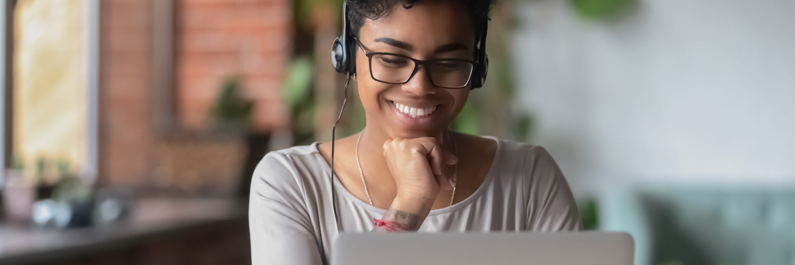 Smiling African girl wear headphones watch online webinar use laptop